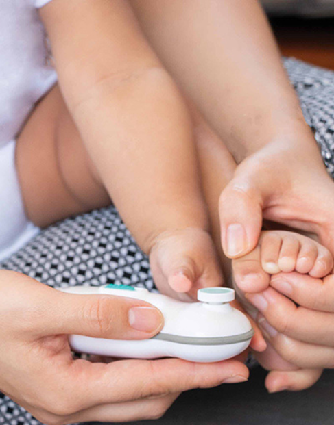 Parent gently trimming a baby’s toenails with an electric nail file